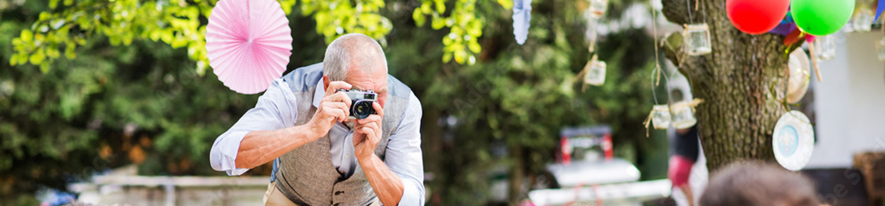 Ein älterer Mann fotografiert bei einer Gartenparty