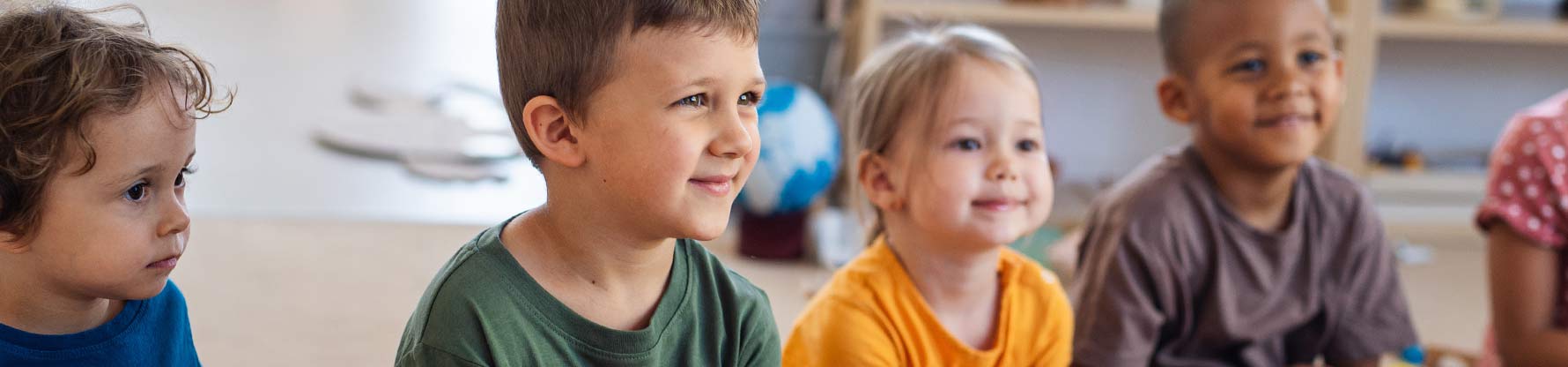 Eine Gruppe Kinder sitzt am Boden und hört zu